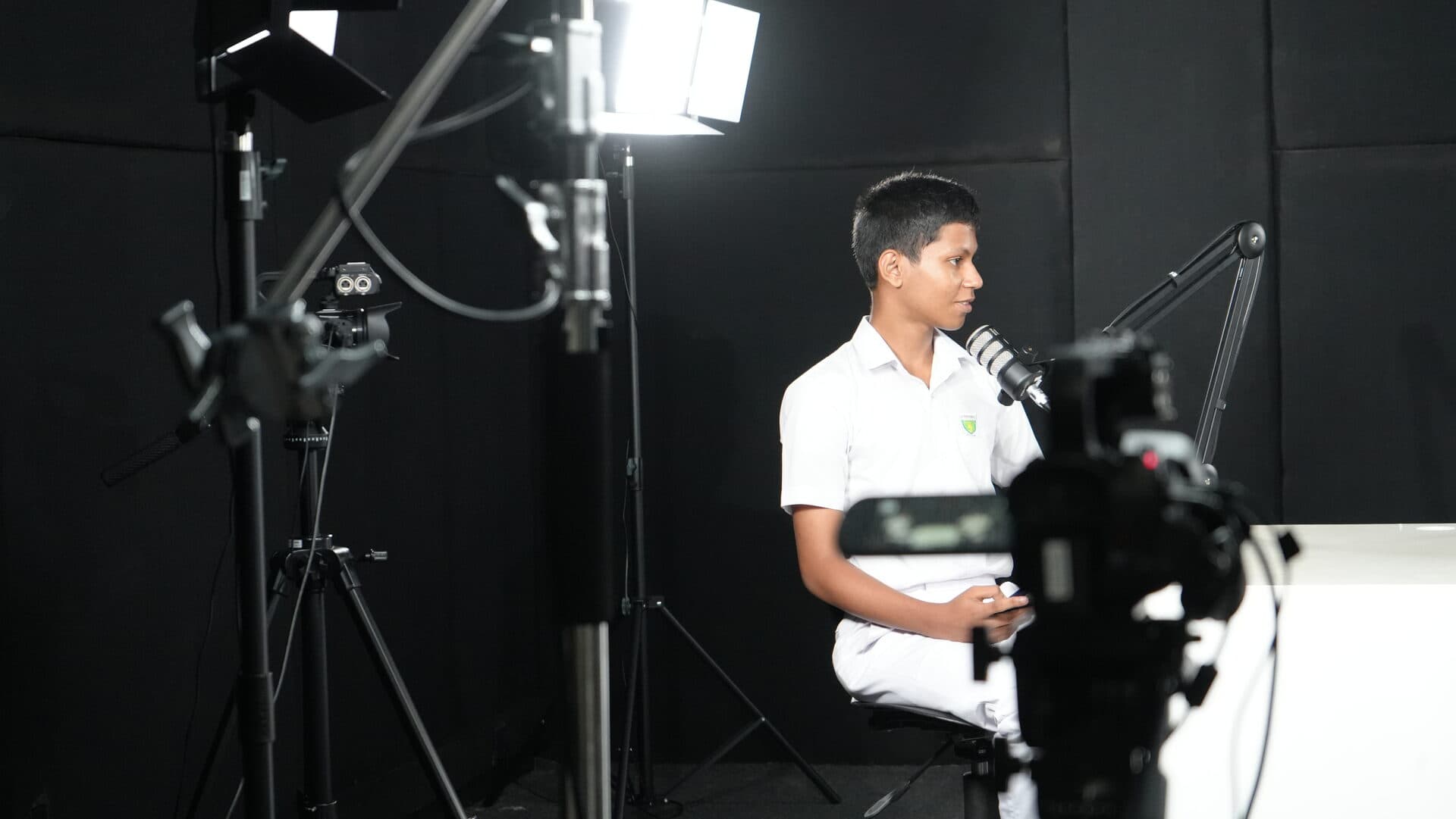 Student recording audio at a professional microphone under studio lighting